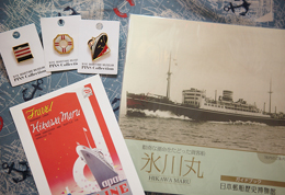 写真左上のピンズや左下のポストカードは異国情緒がただよう。右は歴史が書かれた「氷川丸ガイドブック」。
